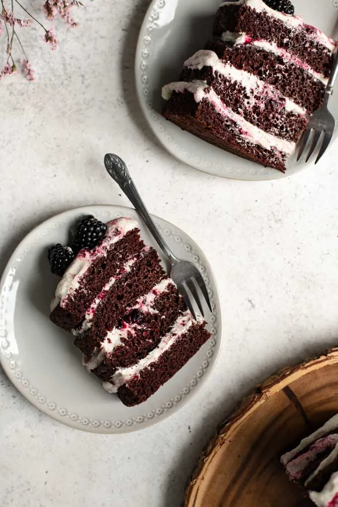 overhead view of 2 slices of the 4-layer cake with the whole cake showing in the corner of the photo