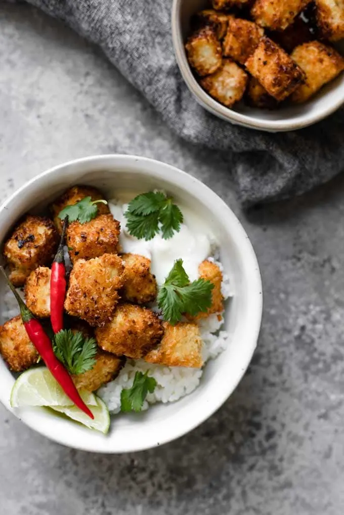 crispy coconut tofu with sushi rice in a bowl, extra tofu on the side