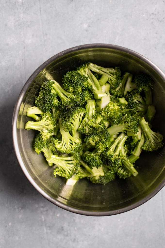 broccoli florets and stems in a mixing bowl tossed with olive oil, lemon juice, salt and pepper