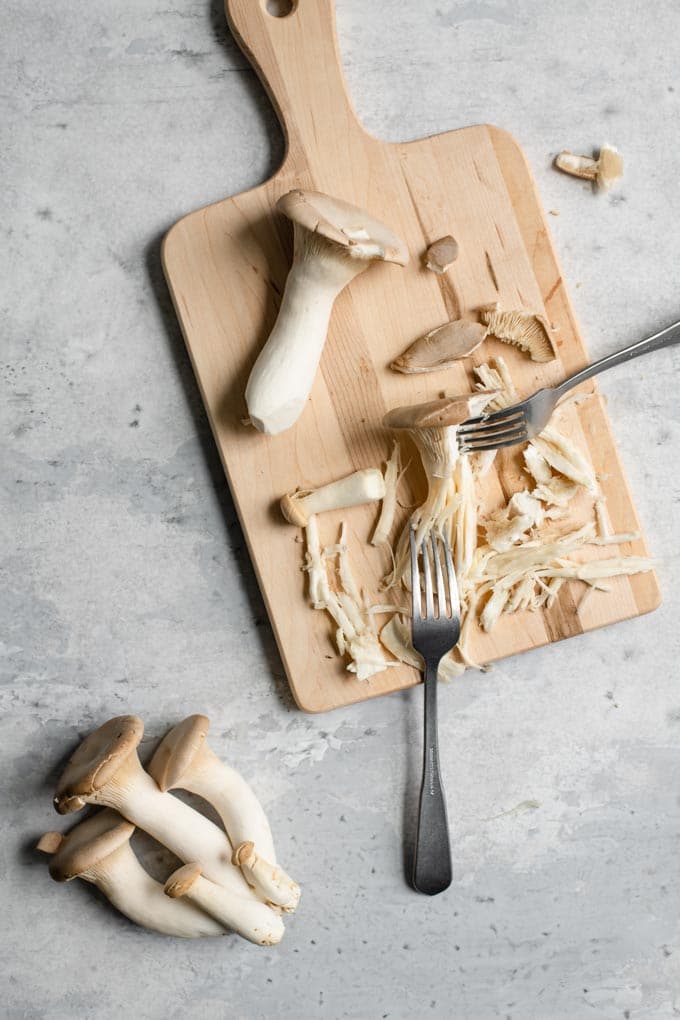 shredding king oyster mushrooms between two forks