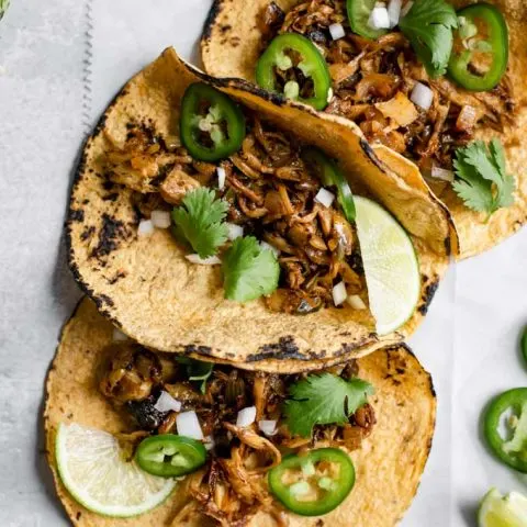 close up of the overhead of the shredded mushroom carnitas tacos with lime, cilantro, and jalapeño as garnish