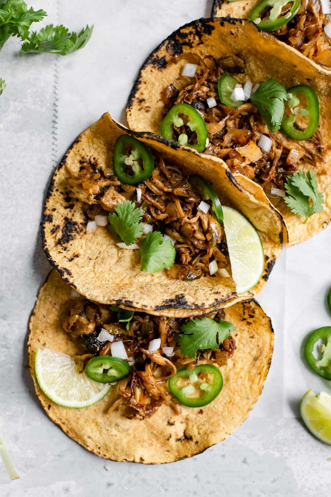 close up of the overhead of the shredded mushroom carnitas tacos with lime, cilantro, and jalapeño as garnish