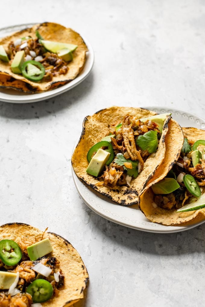 side view of the vegan shredded mushroom carnitas tacos on plates