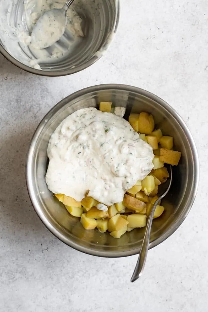 process shot showing the creamy dressing overtop steamed yukon gold potatoes