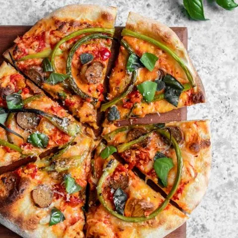 overhead view of garlic scape pizza garnished with fresh basil and oregano