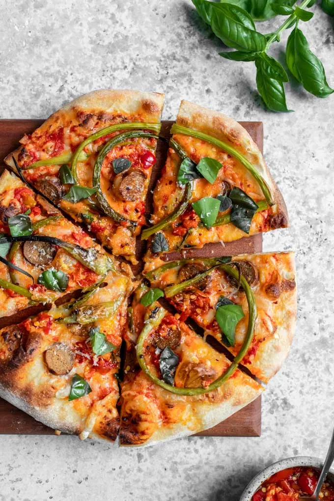 overhead view of garlic scape pizza garnished with fresh basil and oregano