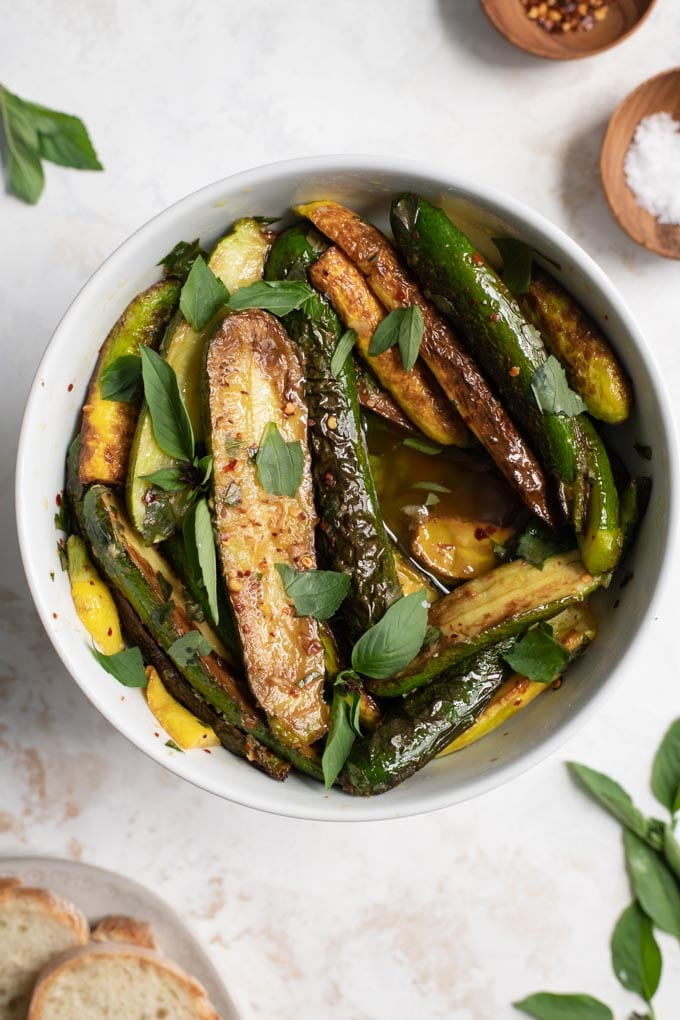 close up of the marinated zucchini garnished with Thai basil and mint and served with bread