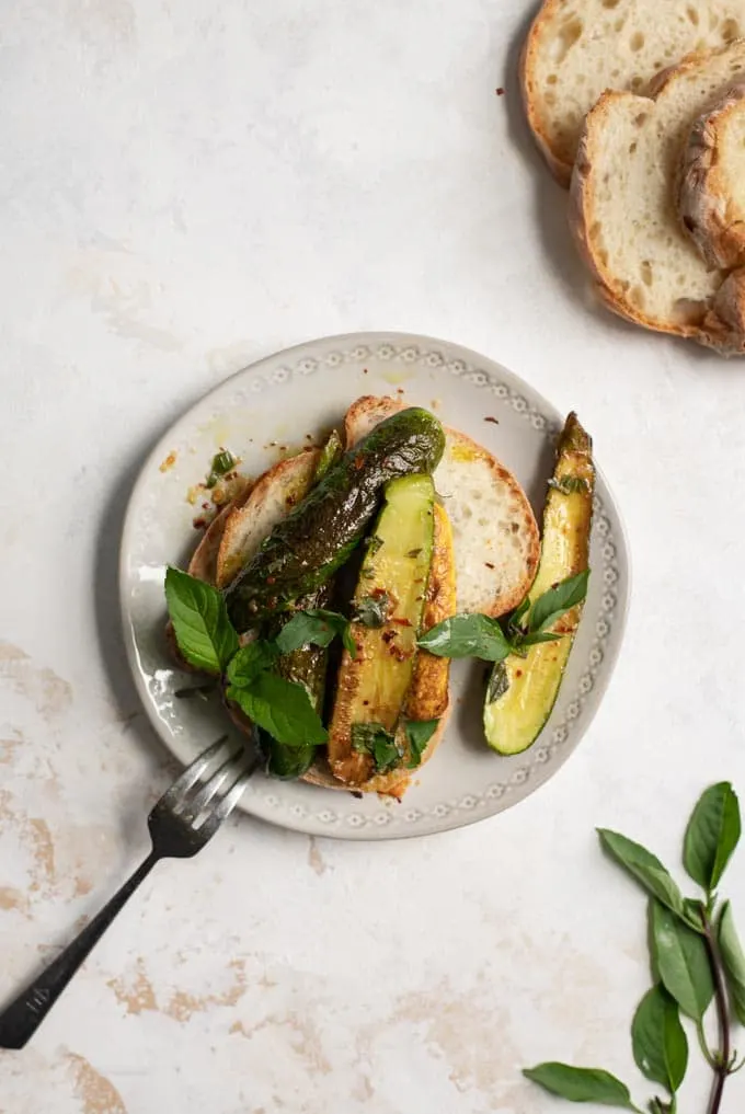 marinated zucchini with Thai basil and mint served over toast on a plate