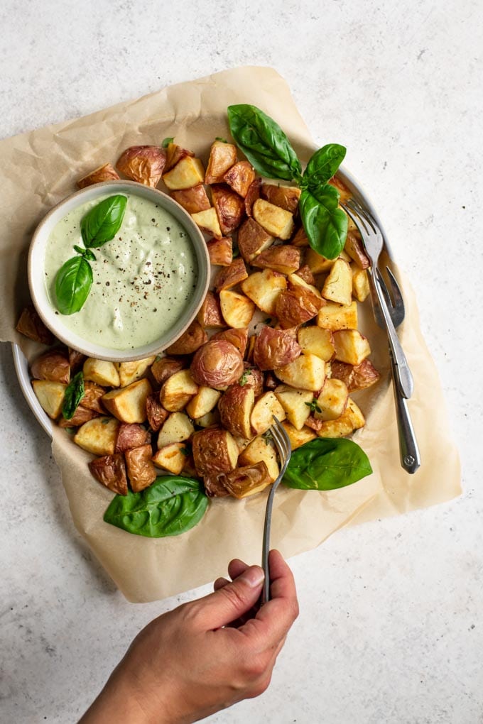 piercing a potato with a fork to dip in the pesto cashew aioli