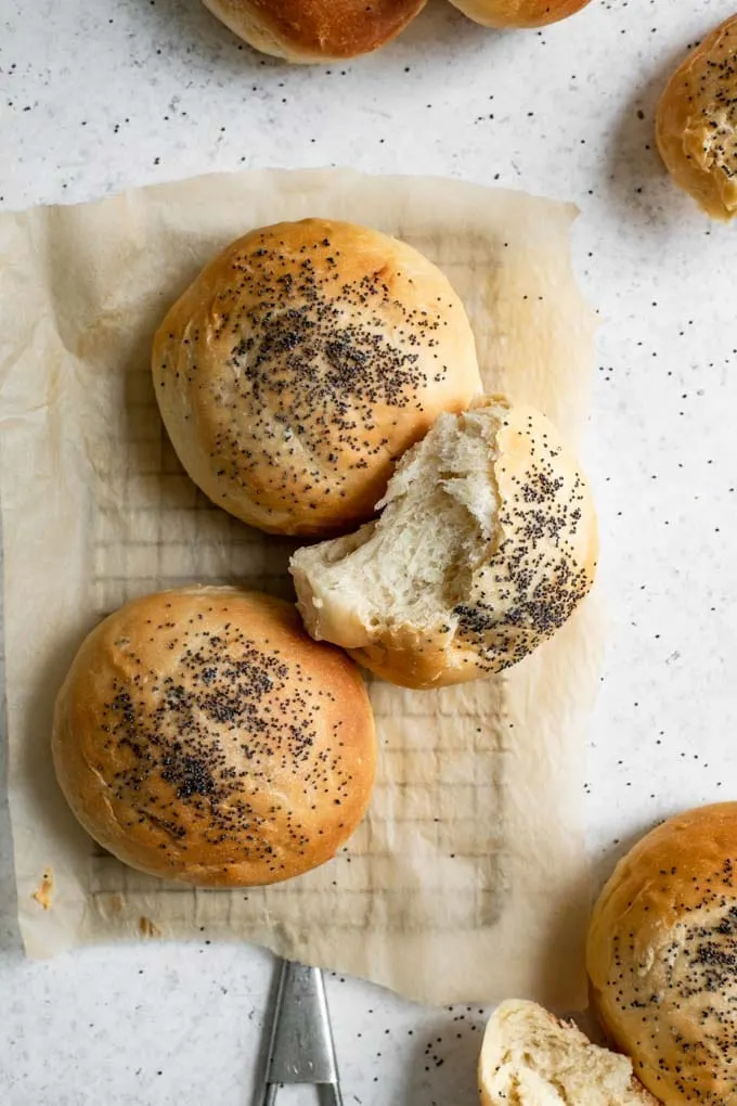 three milk bread buns on a rack, one torn apart to show the soft interior