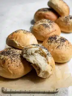 vegan milk bread buns on a cooling rack, one bun torn apart to show soft interior
