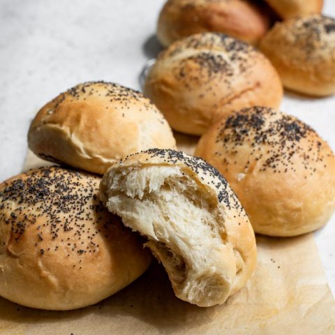 vegan milk bread buns on a cooling rack, one bun torn apart to show soft interior