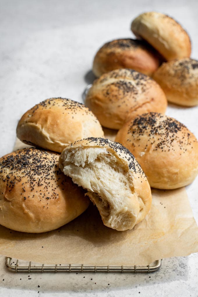 vegan milk bread buns on a cooling rack, one bun torn apart to show soft interior