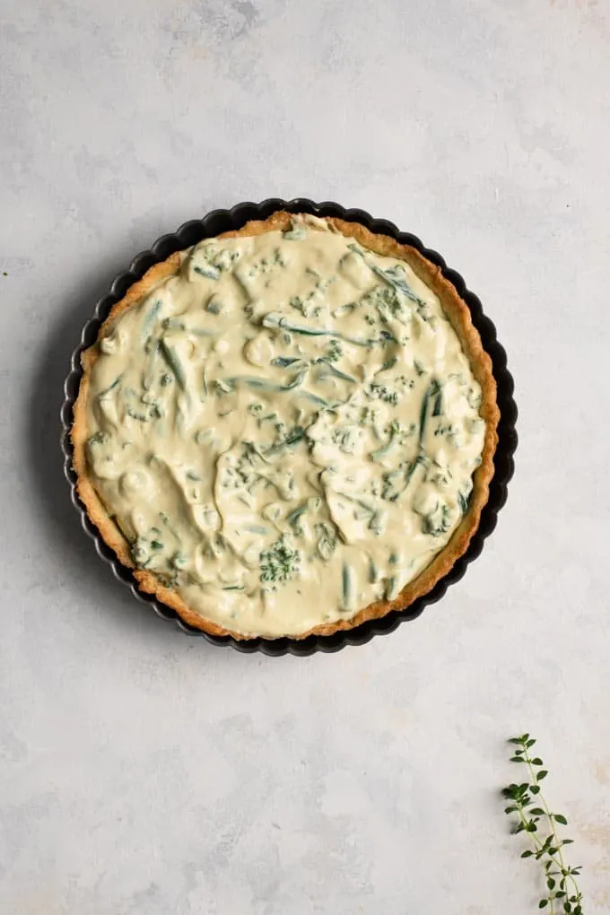 the quiche filling in the blind baked tart pan ready to bake