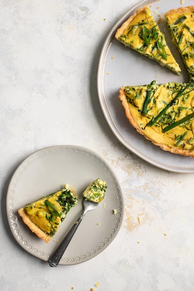 slice of vegan sprouting broccoli quiche with a bite on a fork
