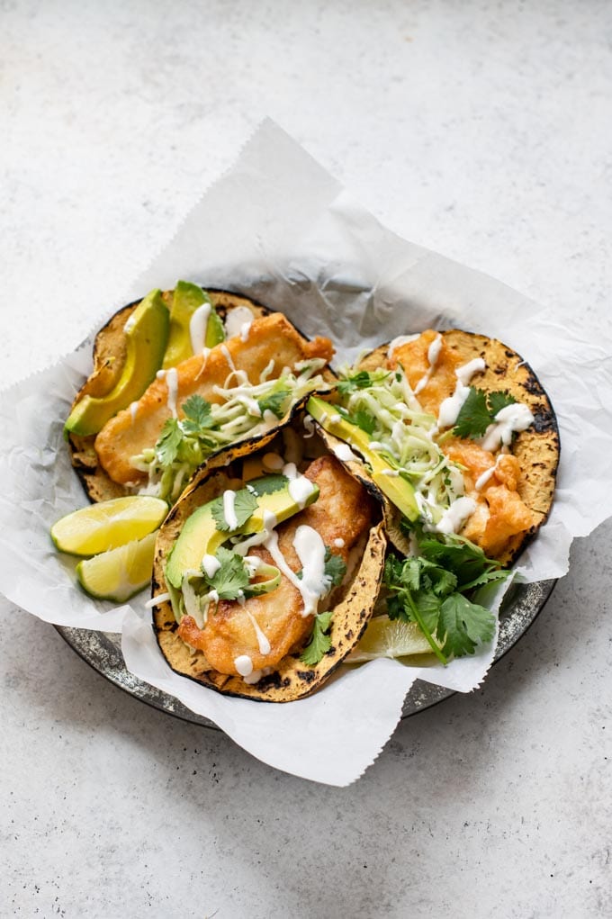 angled view of three Baja tofu tacos on a parchment lined plate