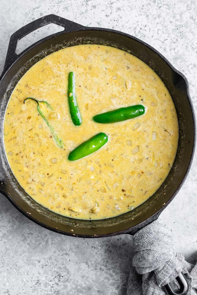 The curry broth before the vegetables are added, in a cast iron skillet with a napkin wrapping the handle