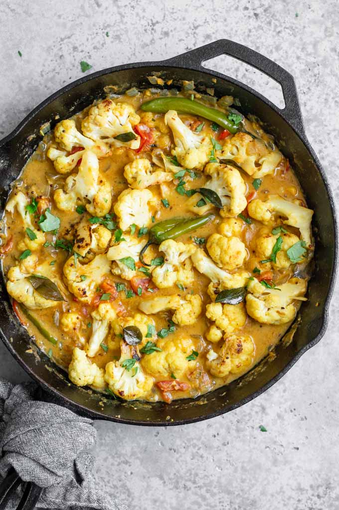 cauliflower moilee curry in a cast iron skillet once it has all been cooked, garnished with cilantro