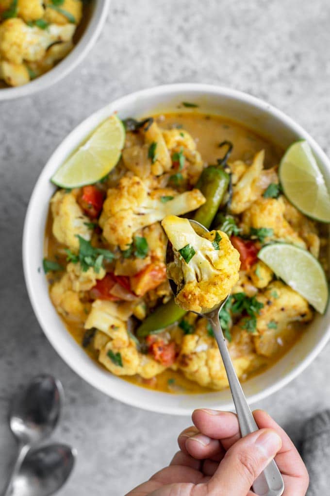 a spoon lifting a cauliflower out of the curry for a close up