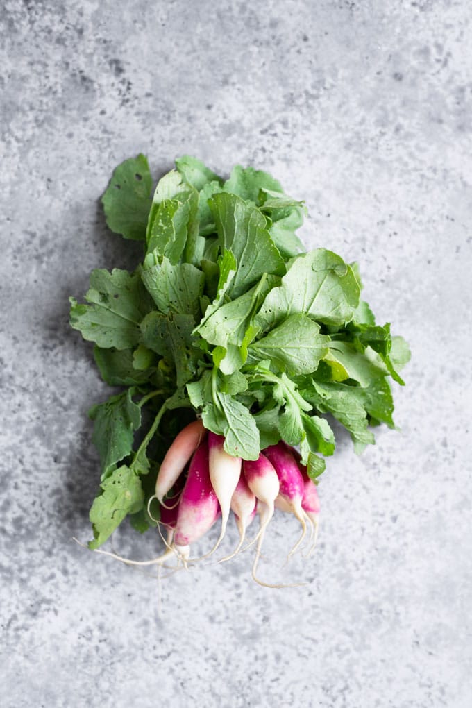 a bunch of french breakfast radishes with the leafy tops still attached