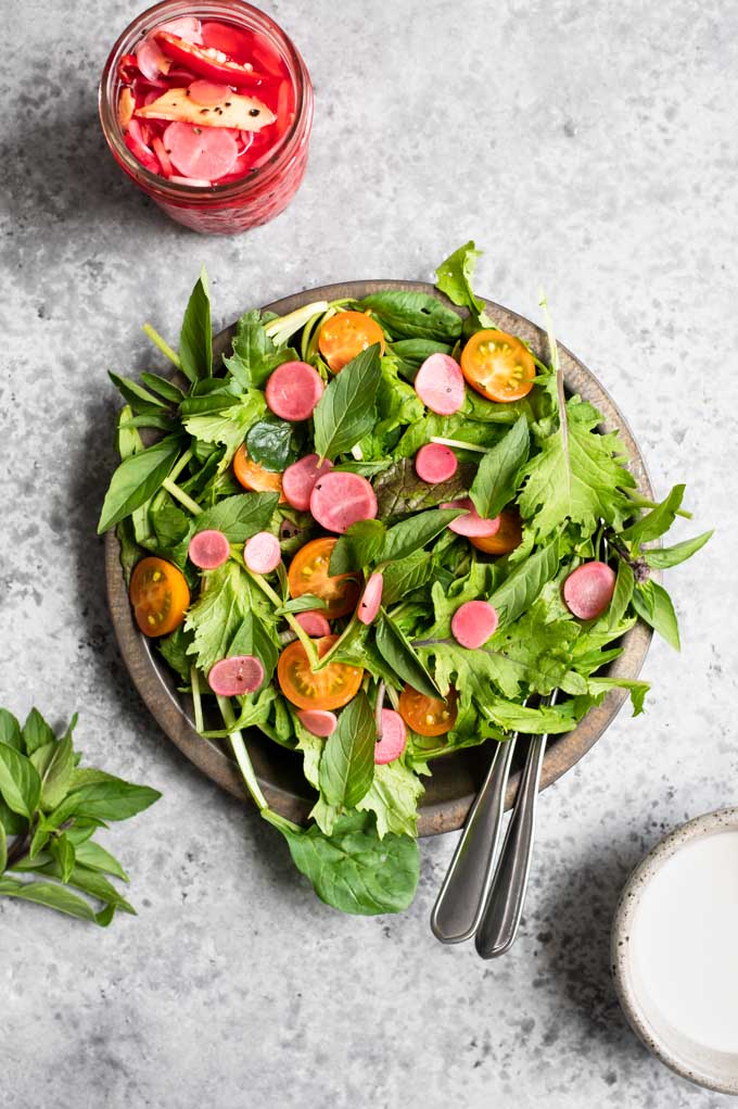quick pickled radishes on top of a simple summer salad, with yellow sungold cherry tomatoes cut in half and a creamy dressing on the side as well as more radishes