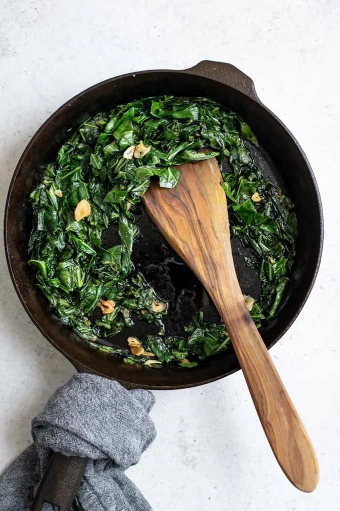 cooked smoky collard greens in a cast iron skillet after cooking