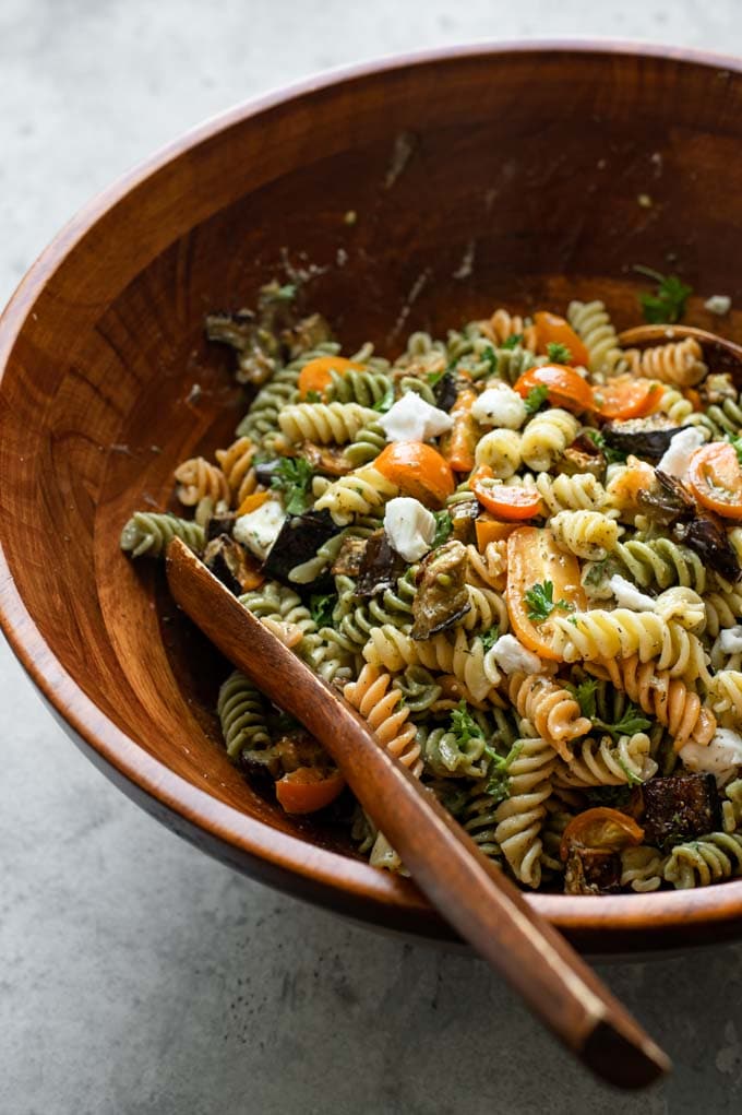 side view of the pasta salad in a large wooden salad bowl after it's been tossed together