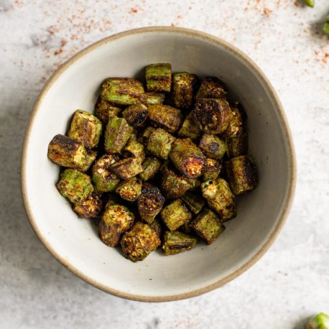 bhindi masala in a small bowl, overhead shot with some okra stems in the corners of the photo