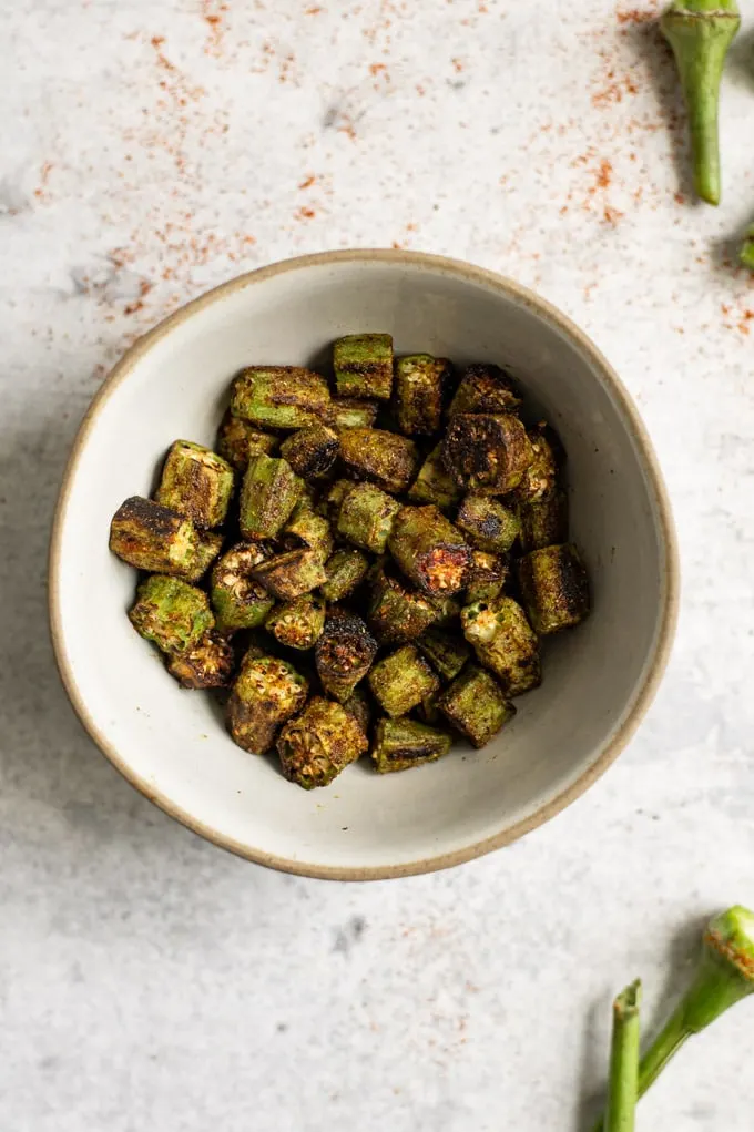 bhindi masala in a small bowl, overhead shot with some okra stems in the corners of the photo