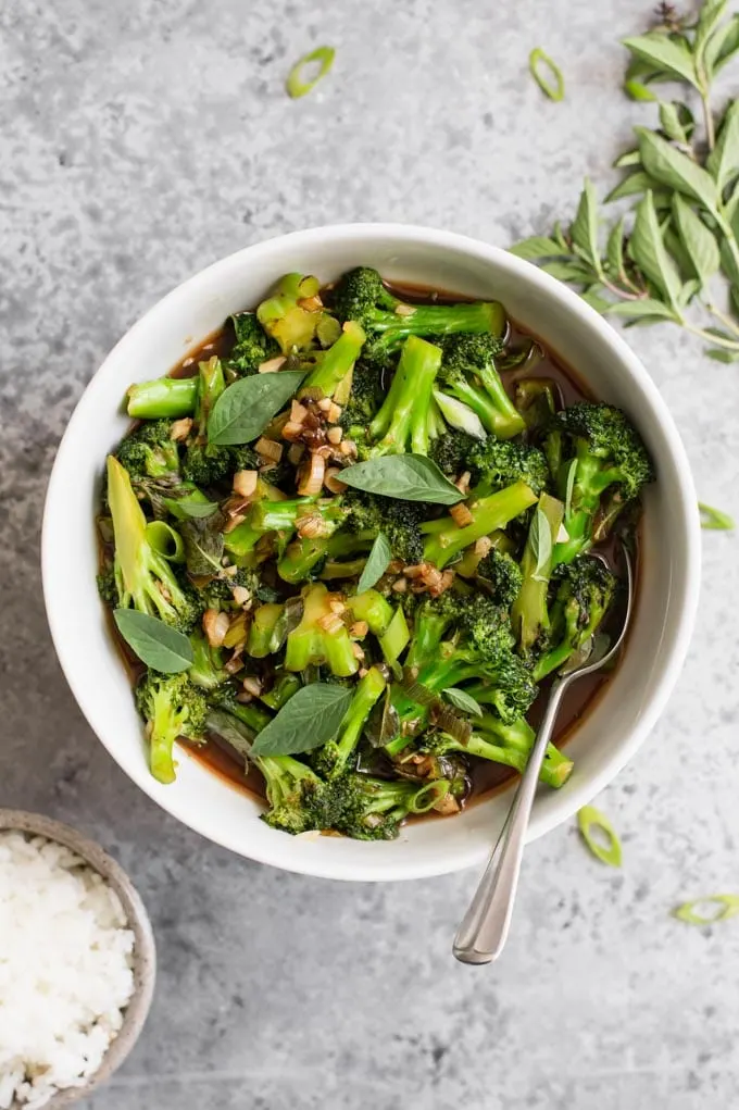 broccoli in garlic sauce served in a bowl with thai basil and jasmine rice