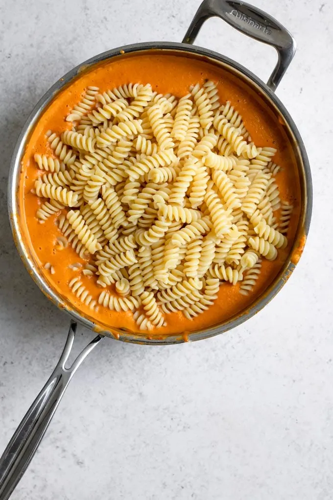 fusilli pasta dumped in a pot of the cheesy curry sauce