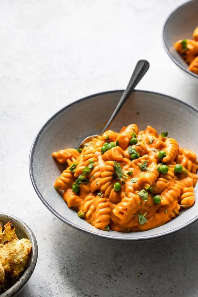 side view of curry mac and cheese with green peas and cilantro