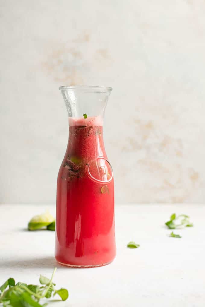 A pitcher full of the watermelon mint agua fresca, with the muddled fruit and mint visible in the pitcher