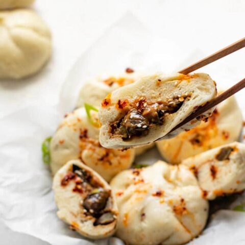 a cut bao held up with chopsticks to show a close up of the filling