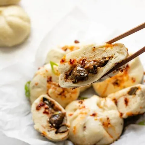 a cut bao held up with chopsticks to show a close up of the filling