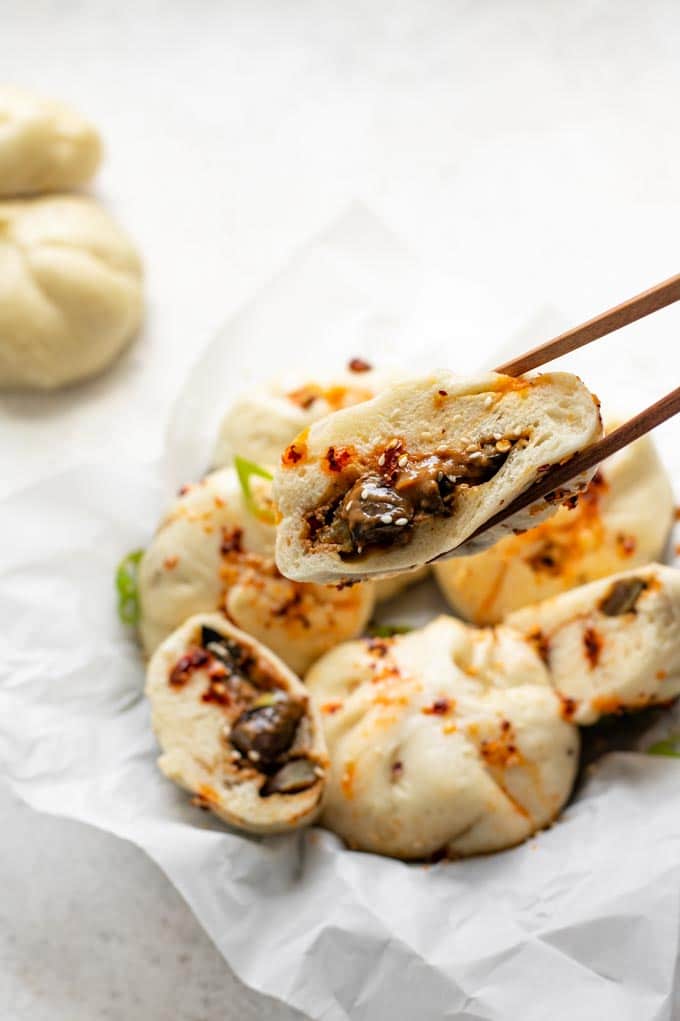 a cut bao held up with chopsticks to show a close up of the filling