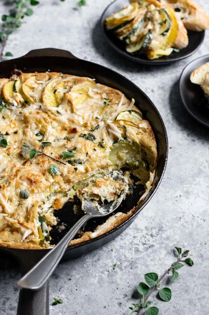 angled view of the potato and zucchini bake with a serving spoon in the dish