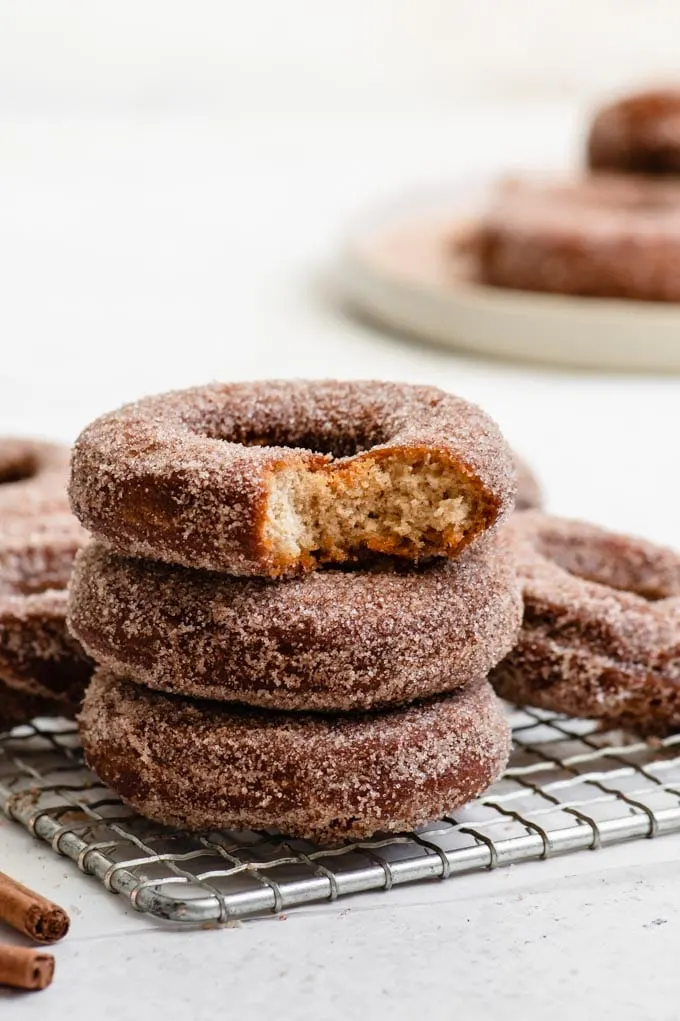 cinnamon sugar apple cider donuts stacked with a bite out of one