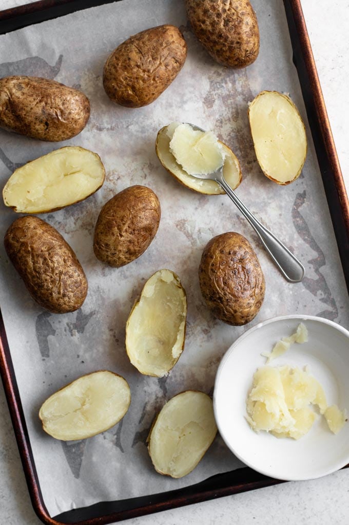 baked potatoes, some cut in half and with the insides scooped out