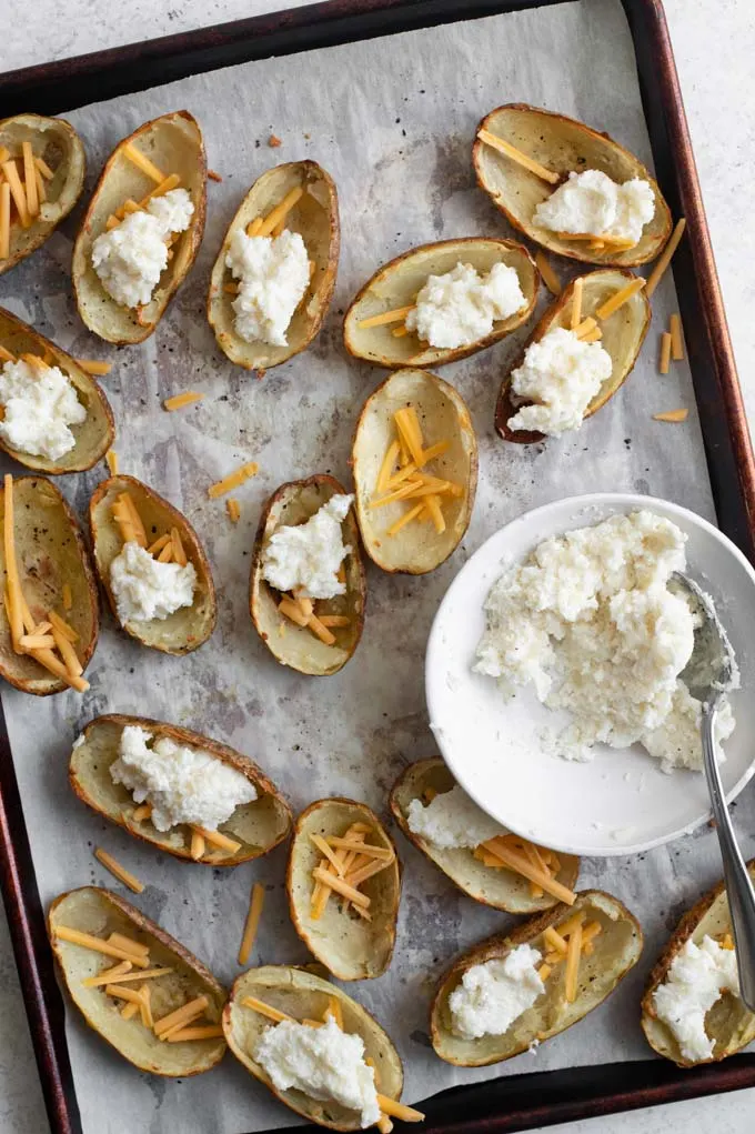 filling the potato skins, with a sprinkling of vegan cheese and mashed potatoes