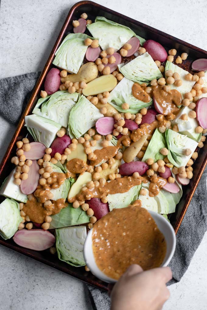 pouring the mustard vinaigrette over the sheet pan