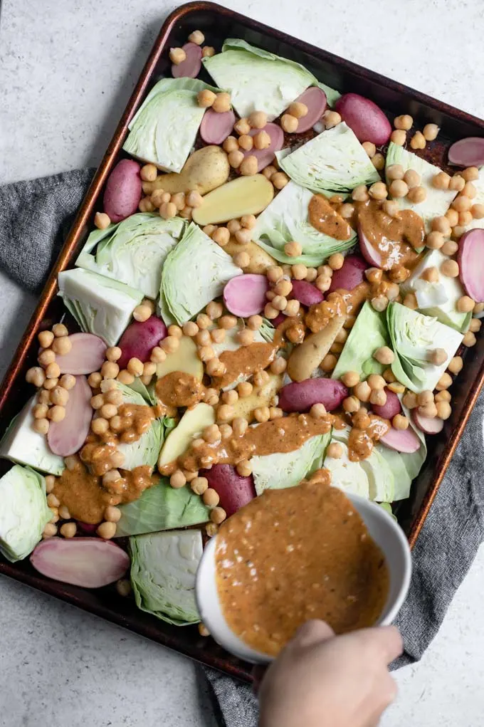 pouring the mustard vinaigrette over the sheet pan