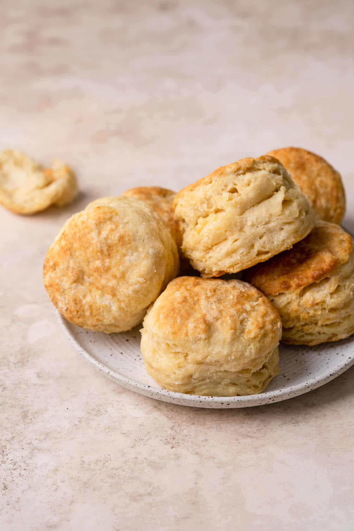 vegan biscuits piled onto a plate with one torn open in the background