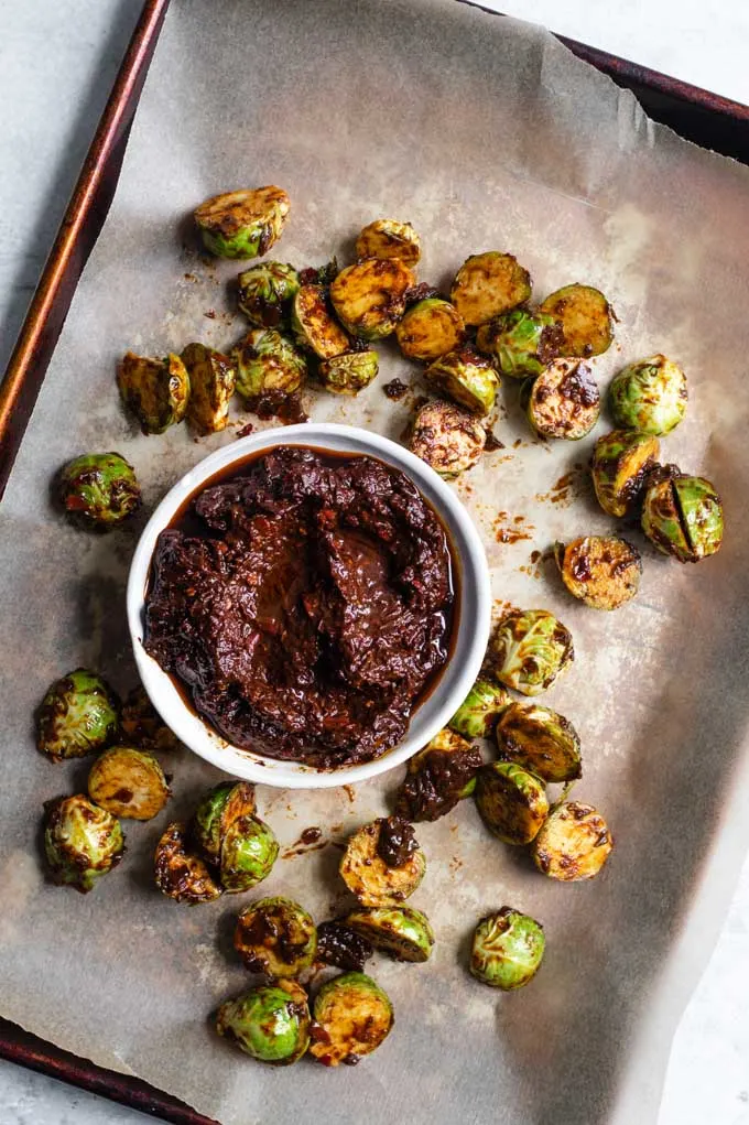 brussels sprouts tossed in harissa and laid on parchment paper lined baking tray