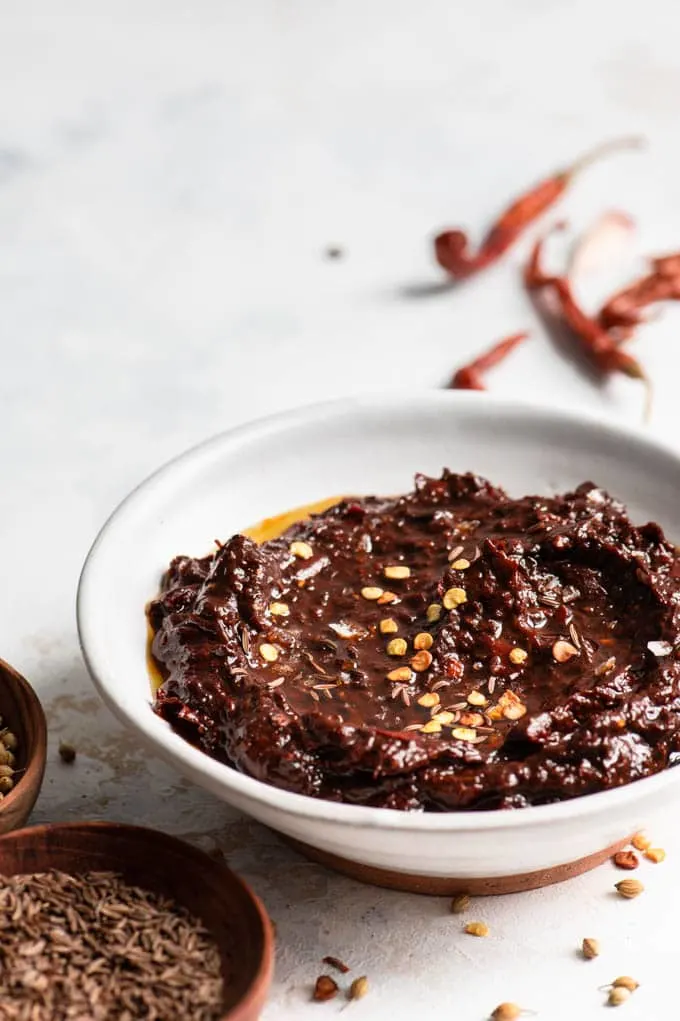 side view of homemade harissa paste drizzled with olive oil and some chili seeds