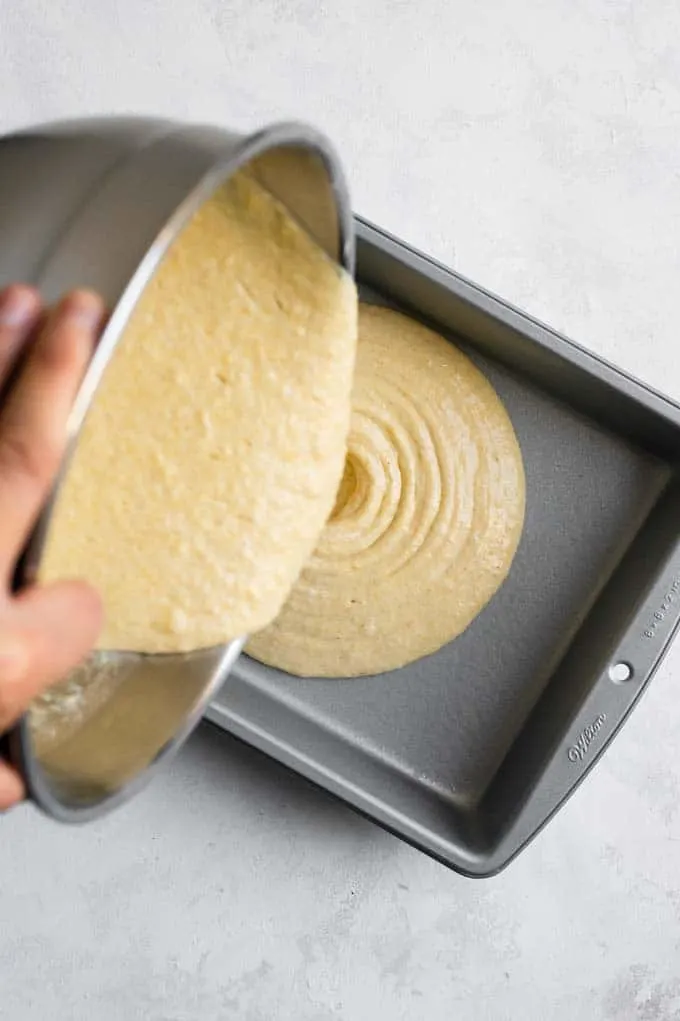 pouring the cornbread batter into a prepared baking pan
