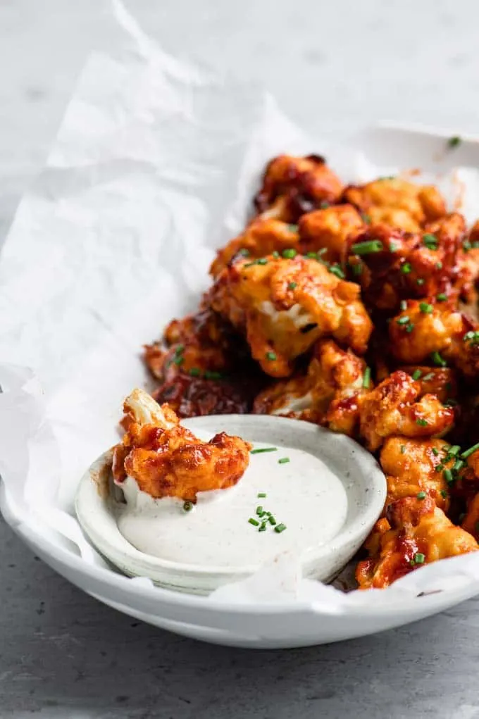 a cauliflower wing dipped into vegan ranch dressing