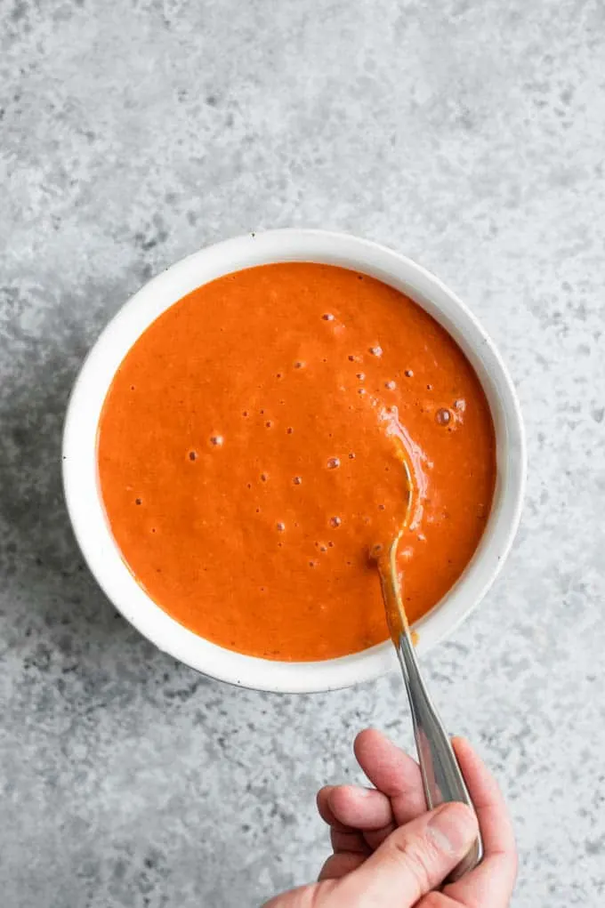 spoon dipping into a bowl of homemade enchilada sauce