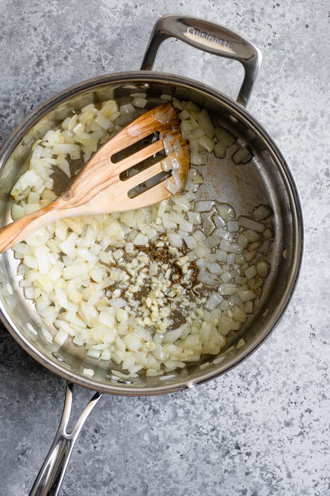 frying onions, garlic, and cumin seed in a pan