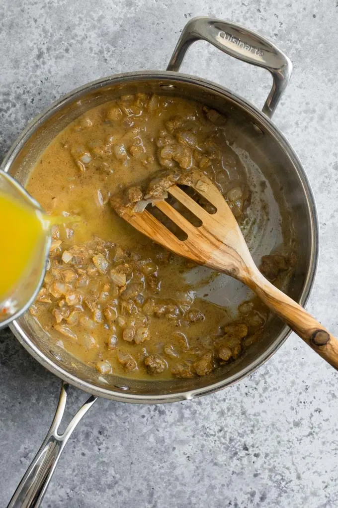 adding broth to pan